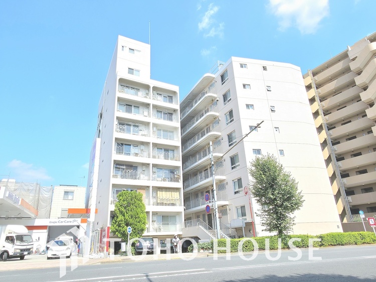 外観 通りに面した、白を基調とした清潔感のあるマンションです。曲線を描く手すりがスタイリッシュな印象を与えます。駅からも近く、周辺にはスーパーや商店街があり、生活しやすい環境です。