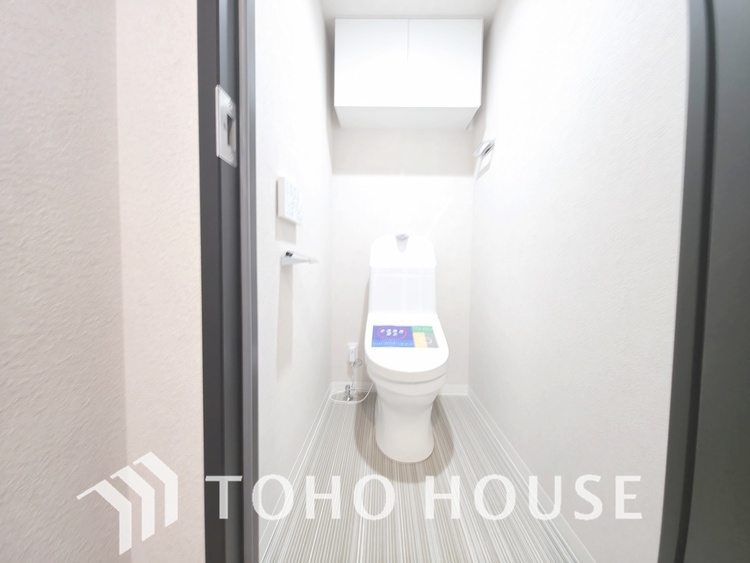 トイレ 白を基調とした、清潔感あふれるトイレです。温水洗浄便座が完備されており、快適に利用できます。上部には収納棚も設置されており、トイレットペーパーなどをストックするのに便利です。