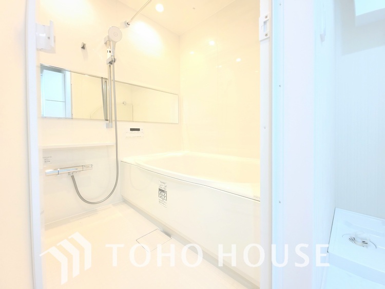 風呂 淡い木目調のパネルと白い浴槽が、清潔感あふれる浴室です。広々とした空間で、足を伸ばしてゆったりと湯船に浸かれます。毎日の疲れを癒す、至福のバスタイムを過ごせます。