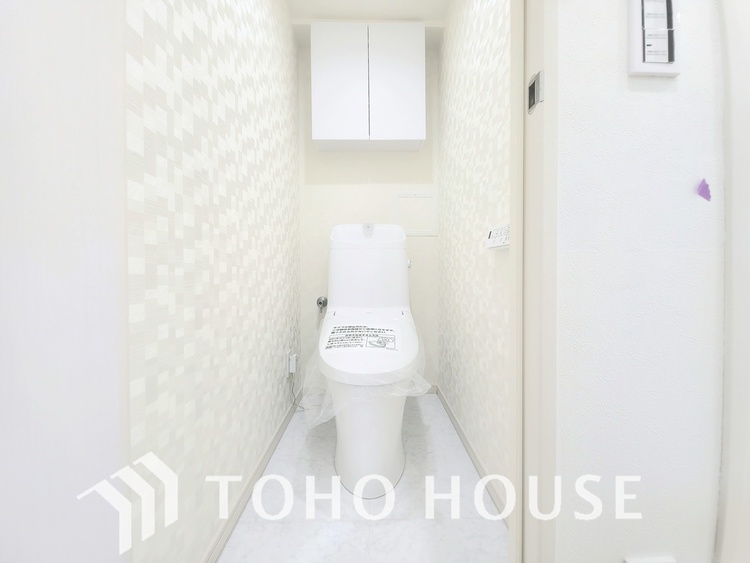 トイレ 温かみのある木目調のカウンターが目を引く、清潔感あふれるトイレです。温水洗浄便座と手洗い器も完備。上下に収納スペースもあり、すっきりとした空間を保てます。