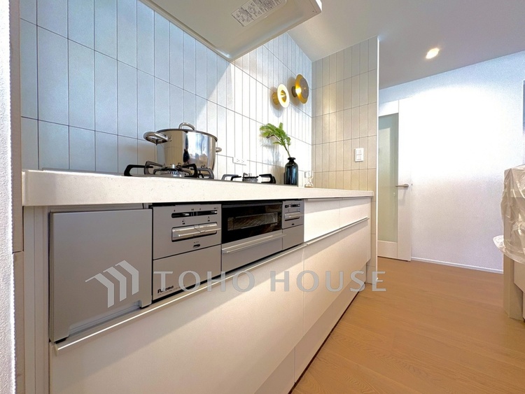 キッチン 【Kitchen】湯気が立ちのぼるたび、会話が弾む。リビングを見渡せる配置で、家族の気配を感じながら料理ができます。日常をやさしく支える空間です。