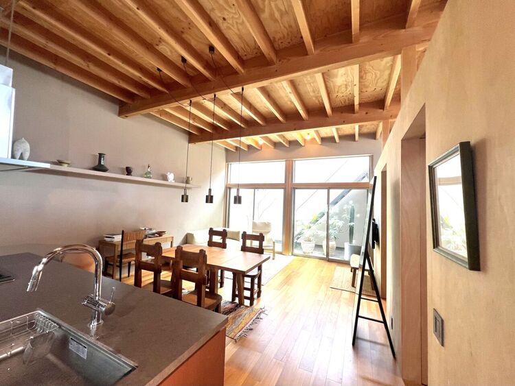 居間 無垢材の質感と梁見せ天井が織りなす、こだわり溢れる空間。ナチュラルな素材感とミニマルなインテリアが調和し、洗練された暮らしを実現。ペンダントライトが空間のアクセントとなり、昼夜で異なる表情を楽しめます