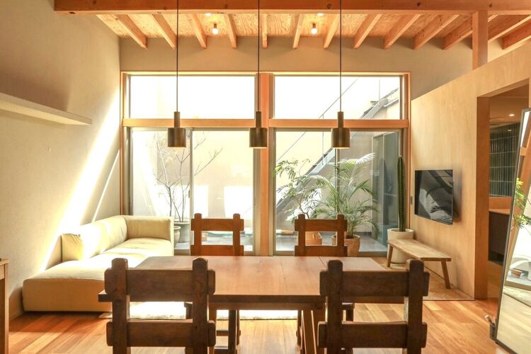 居間 吹抜け天井と大開口が生む圧倒的な開放感。無垢材の梁と木質の温もりに包まれ、光と緑が調和する上質なLDK空間。設計美と居心地を兼ね備えた、日常を格上げする住まいの中心です。