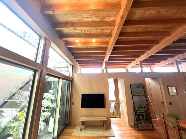 居間 開放感あふれる高天井リビング。梁を活かした木の温もりと、大きな窓から差し込む豊かな自然光が心地よい空間を演出します。中庭を望む設計により、外からの視線を気にせずプライベート感も確保。