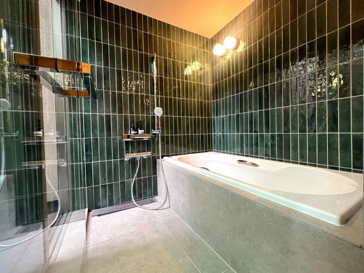風呂 クリアガラスのバス扉が空間に広がりと抜け感を創出。視線が繋がることで一体感のあるホテルライクな設えに。上質なタイルと調和し、日常の入浴時間を特別なひとときへと昇華します。