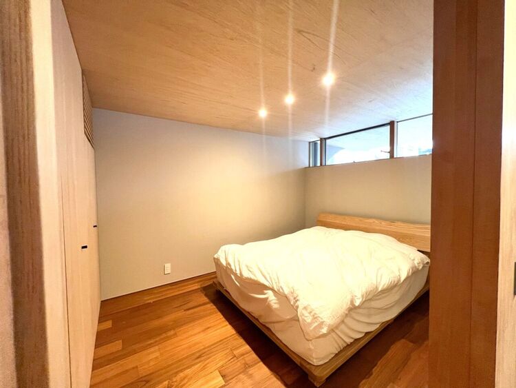 内装 落ち着いた光が差し込む1階主寝室。無垢材の温もりと木目の美しさが調和し、静寂と安らぎに包まれる上質な空間を演出。設計士の意図が息づく、日常を豊かにするプライベート空間です。