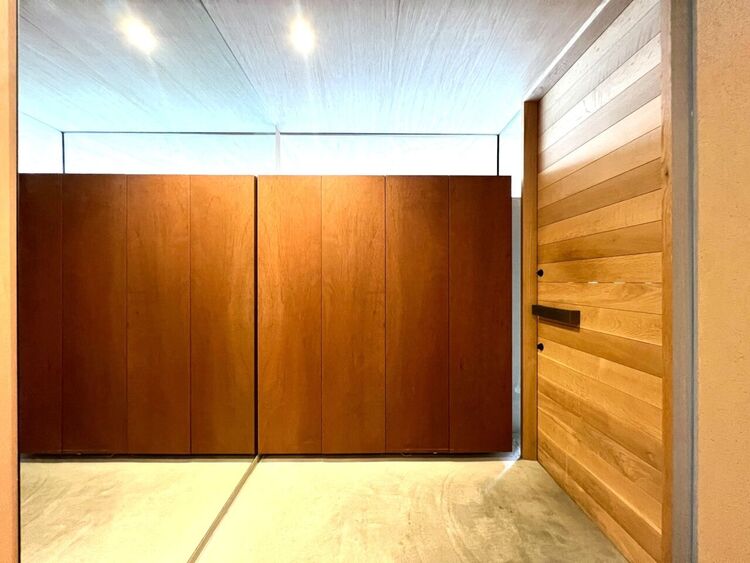 玄関 左官仕上げの美しい外観が印象的なファサード。曲線を描くアプローチとビルトインガレージが高いデザイン性と実用性を両立。外部からの視線を遮る設計で、都心におけるプライバシー性も確保された邸宅です。